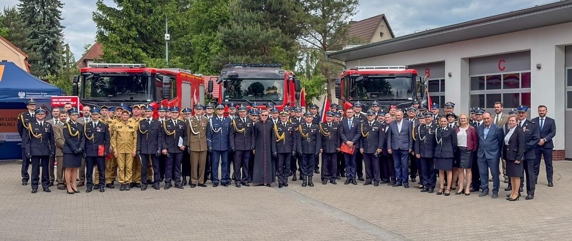 Zdjęcie grupowe uczestników i zaproszonych gości na tle pojazdów ratowniczo gaśniczych 