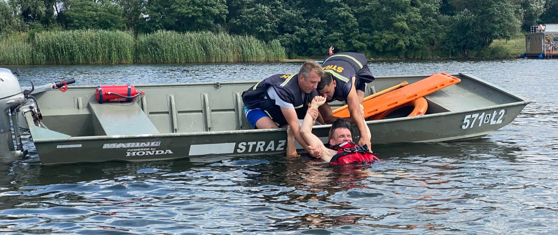 Strażacy na łódce wyciągający poszkodowanego z wody