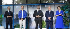 Na sali przed banerami z napisem "Polska sięga gwiazd" stoi pięć osób, drugi od lewej Sławosz Uznański-Wiśniewski, obok minister Kulasek, w tle duże okna.