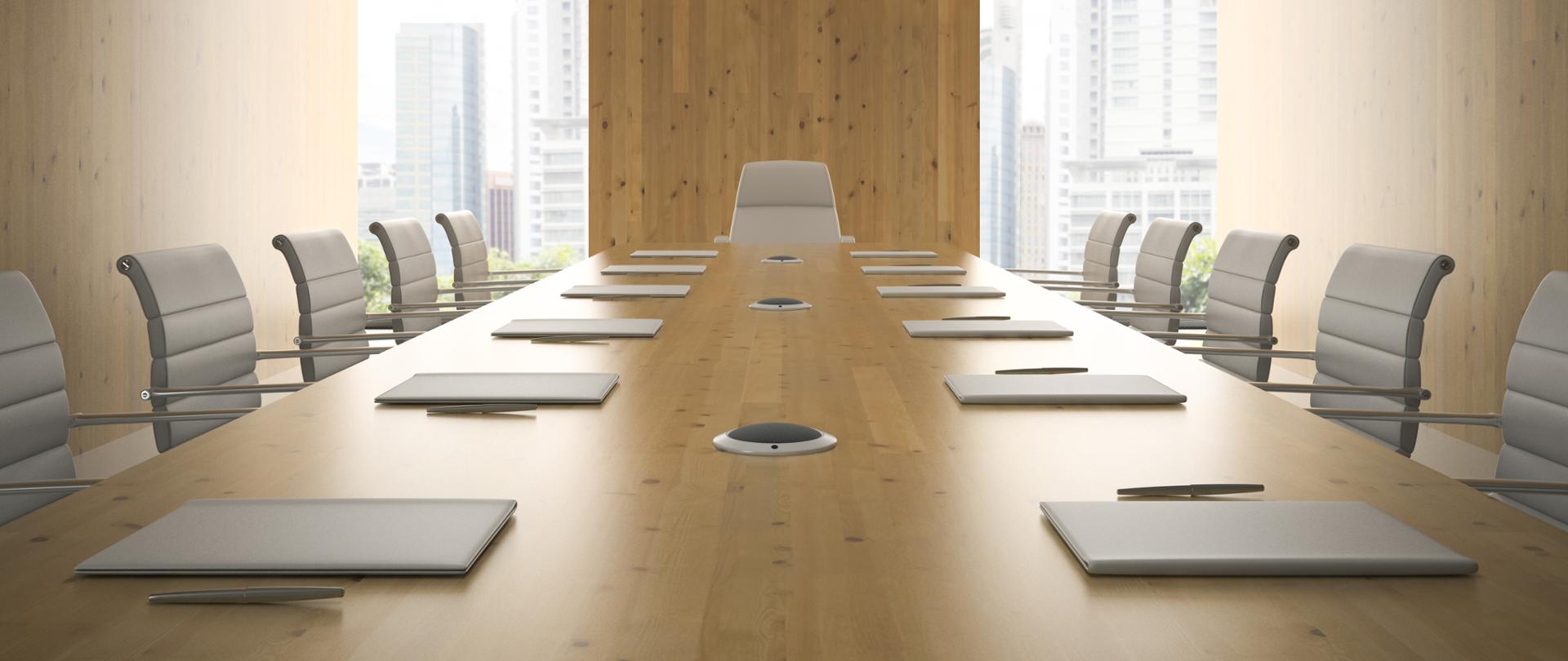 Nowoczesna sala konferencyjna, białe fotele, na stole długopisy i notatniki