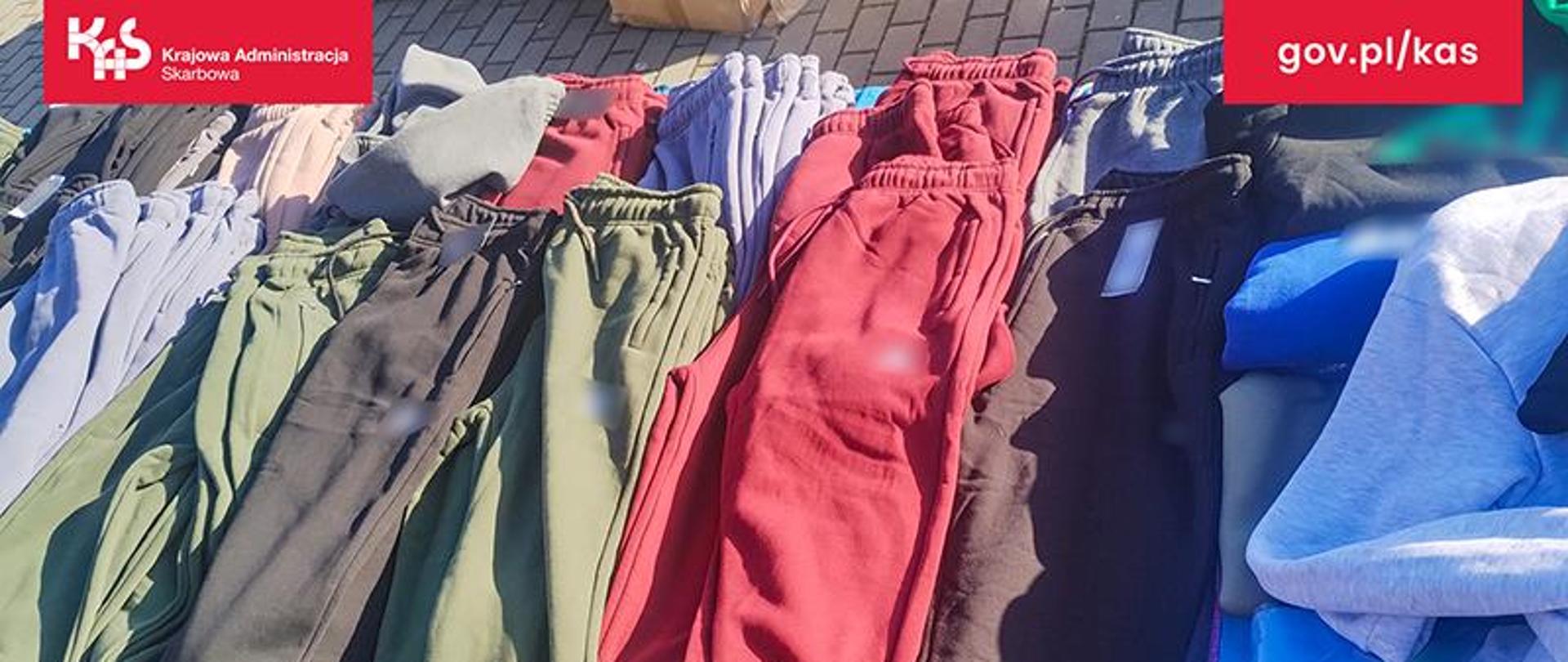 Na stole leżą spodnie dresowe w różnych kolorach.