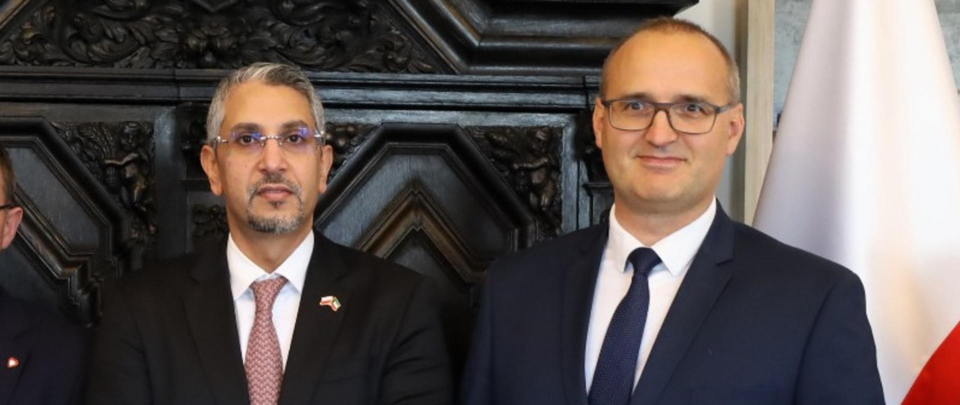 dwóch mężczyzn - ambasador i wicewojewoda stoją w gabinecie na tle polskiej flagi