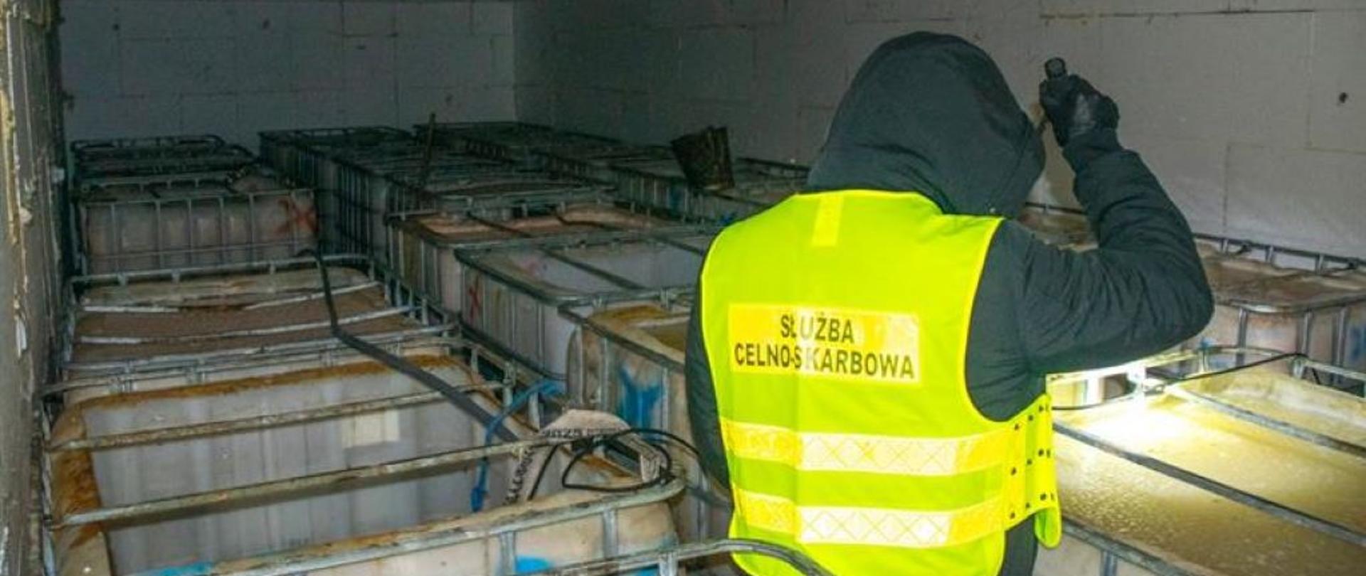 ciemne pomieszczenie, funkcjonariusz ogląda mauzery wypełnione alkoholem