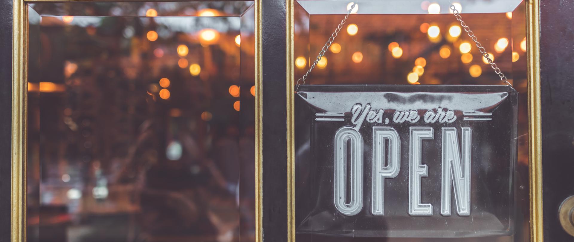 tabliczka na drzwiach z napisem w języku angielskim Tak, jesteśmy otwarci