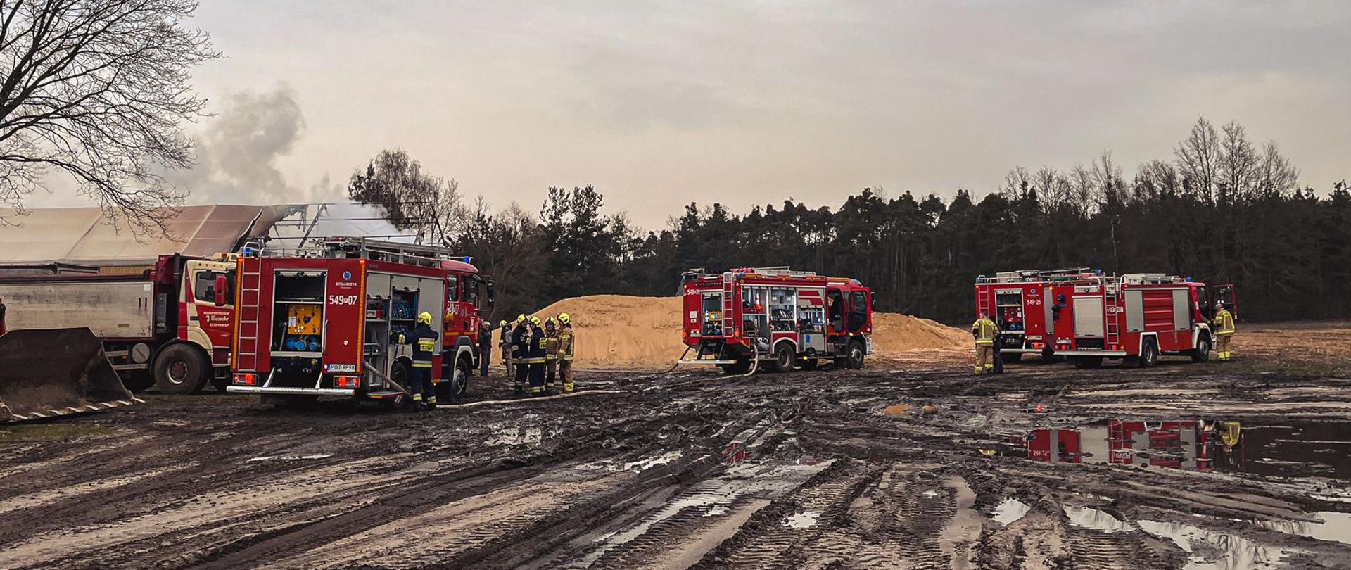 Samochody strażackie z strażakami w trakcie działań gaśniczych
