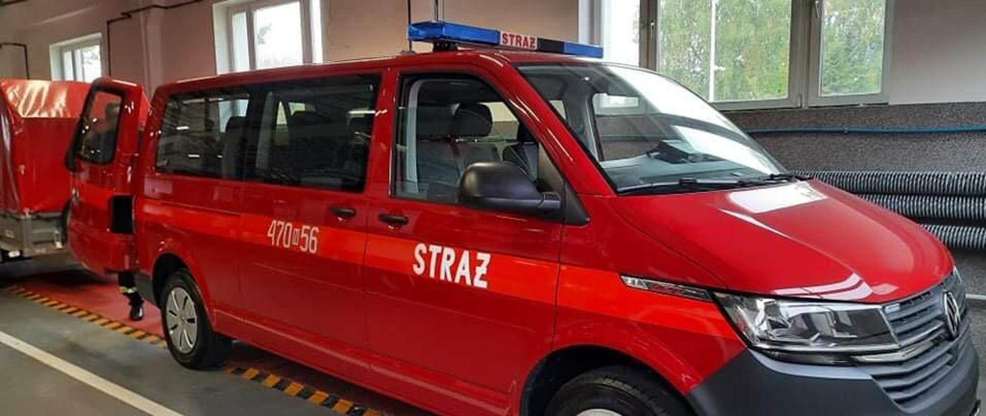 Zdjęcie przedstawia czerwonego busa zakupionego ze środków FUNDUSZU PRZECIWDZIAŁANIA COVID – 19. Zdjęcie zrobione w garażu JRG Kętrzyn i widać prawą stronę samochodu.