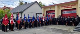 „Poczty sztandarowe oraz strażacy zgromadzeni przed strażnicą OSP Potworów podczas uroczystości jubileuszowych związanych ze 100-leciem jednostki.”