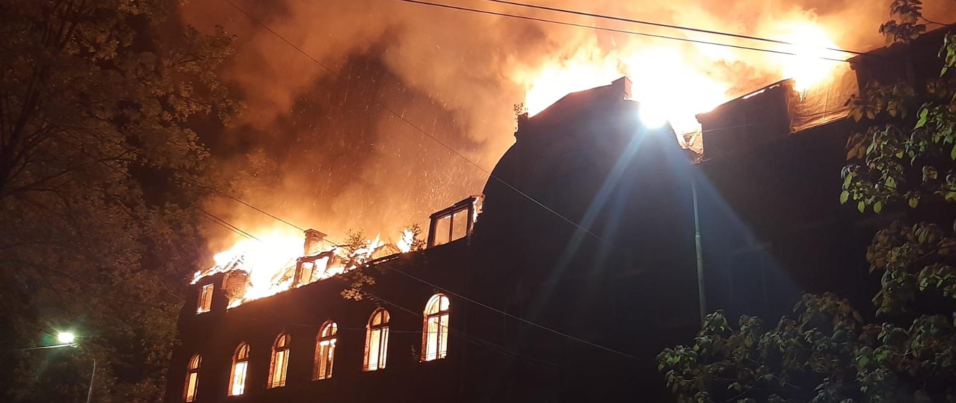 Na zdjęciu widoczny rozwinięty pożar dachu dwupiętrowego budynku