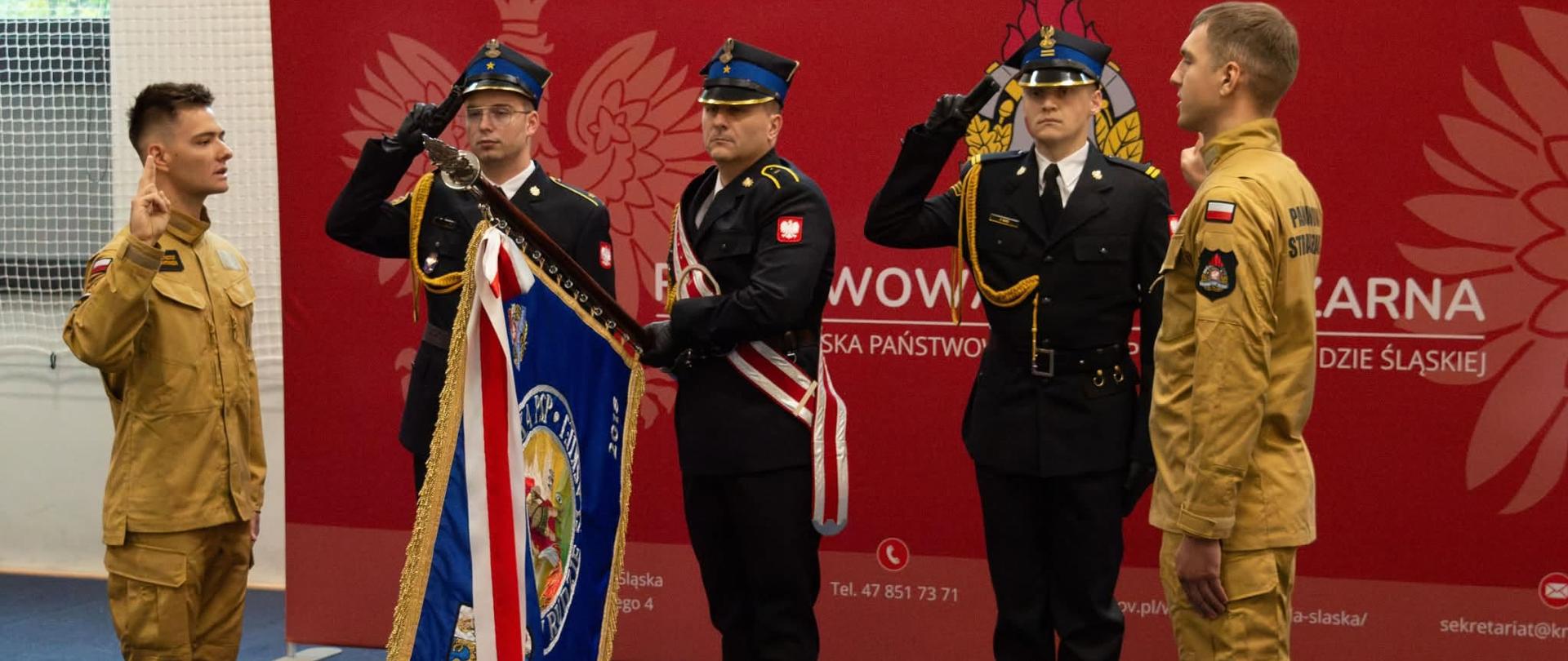 Zdjęcie przedstawia strażaków, którzy są w trakcie składania uroczystości ślubowania na sztandar Komendy Miejskiej Państwowej Straży Pożarnej w Rudzie Śląskiej.
