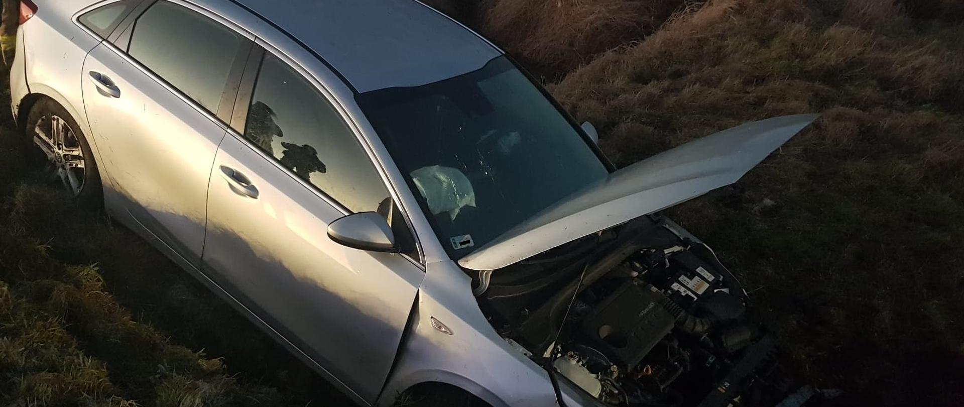 Zdjęcie przedstawia samochód osobowy po zdarzeniu drogowym. Samochód znajduje się w przydrożnym rowie.