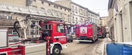 Samochody pożarnicze i radiowóz znajdują się na drodze dojazdowej do miejsca pożaru.
