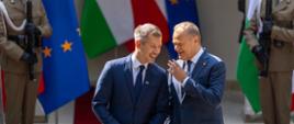Na zdjęciu premier Donald Tusk (po prawej) oraz premier Węgier Péter Magyar (po lewej). Premierzy stoją na czerwonym dywanie. W tle widać flagi (Polski, Węgier oraz UE), dwóch żołnierzy oraz front budynku.