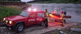 samochód terenowy strażacki z łodzią przy brzegu rzeki
