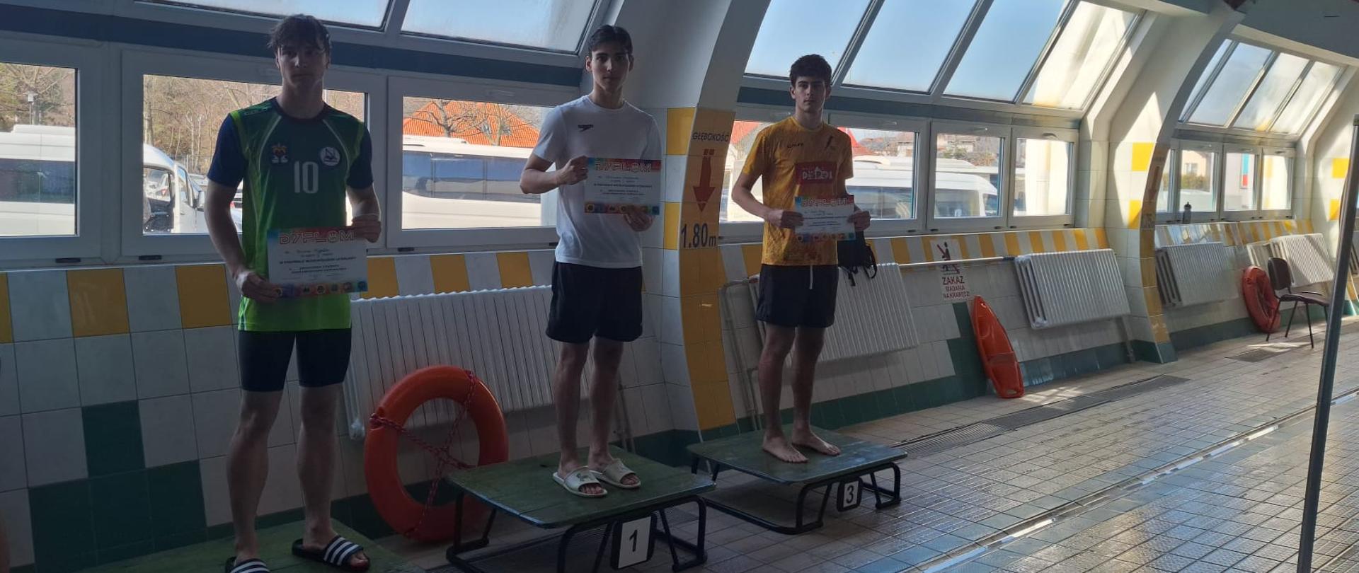 Widoczne podium ze zwycięzcami zrobione na pływalni.