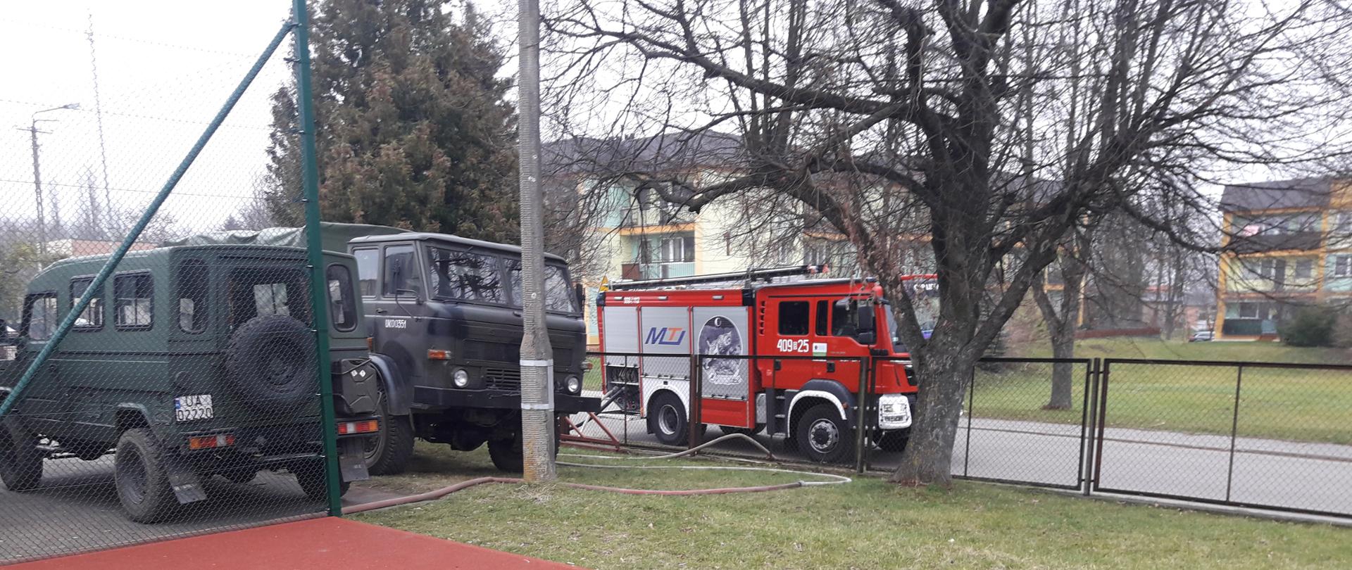Na zdjęciu widać samochód pożarniczy oraz samochody wojskowe.
