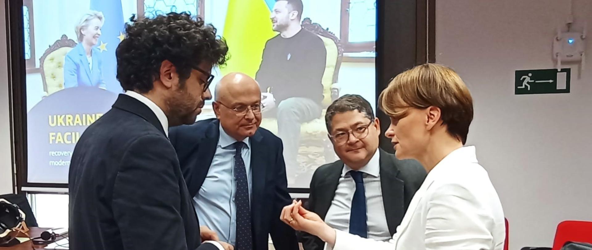 Cztery osoby stoją i rozmawiają ze sobą. Pierwsza z prawej stoi wiceminister Jadwiga Emilewicz.