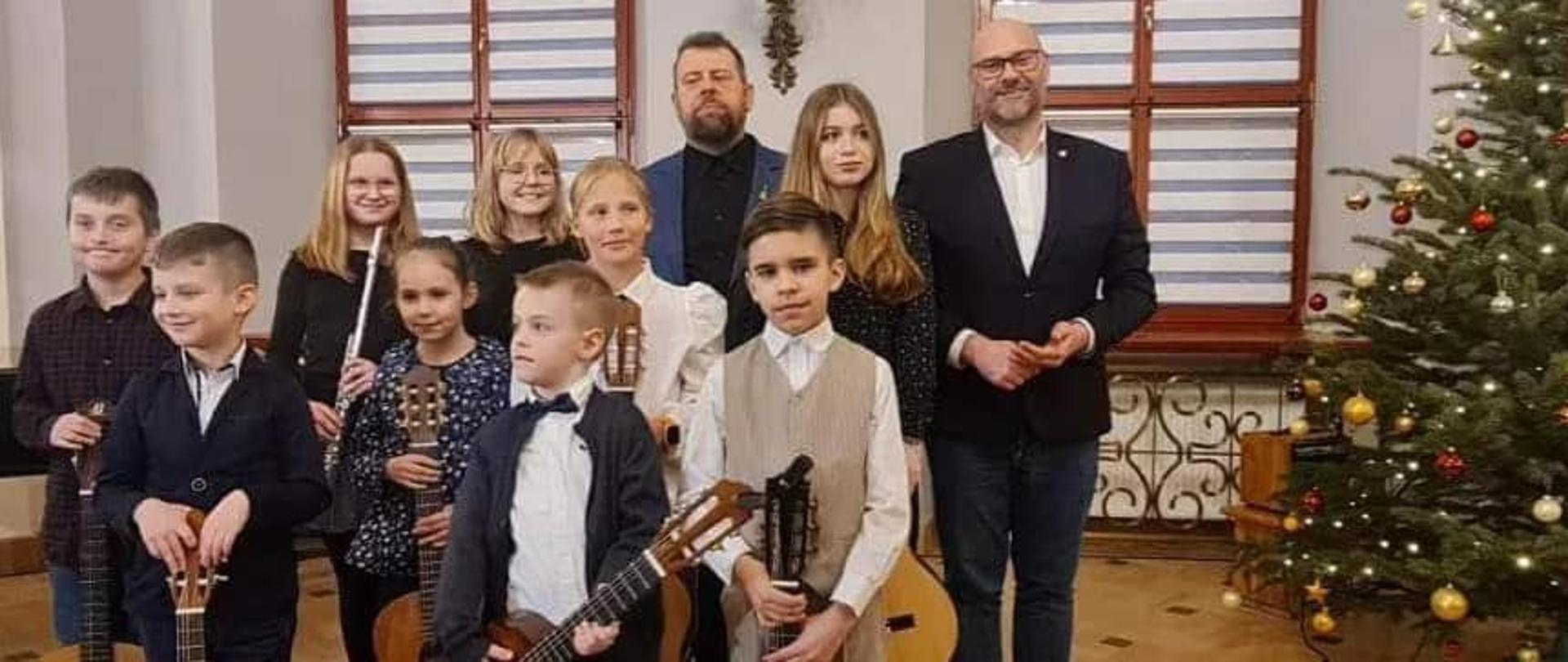 Grupa dzieci trzymająca gitary pozuje do zdjęcia grupowego wraz z nauczycielem Witoldem Kozakowskim oraz Burmistrzem miasta Kłodzka Michałem Piszko