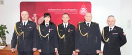 Na zdjęciu widnieją funkcjonariusze odchodzący na zaopatrzenie emerytalne z dniem 31.01.2024, w towarzystwie Komendanta i zastępcy Komendanta Miejskiego PSP. Funkcjonariusze ubrani są w umundurowanie galowe.