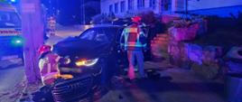 Na zdjeciu widać wypadek samochodu osobowego, ktory uderzyl w słup energetyczny, strażacy prowadzą działaąnia przy pojeździe, w oddali widać samochód straży pożarnej i ZRM.