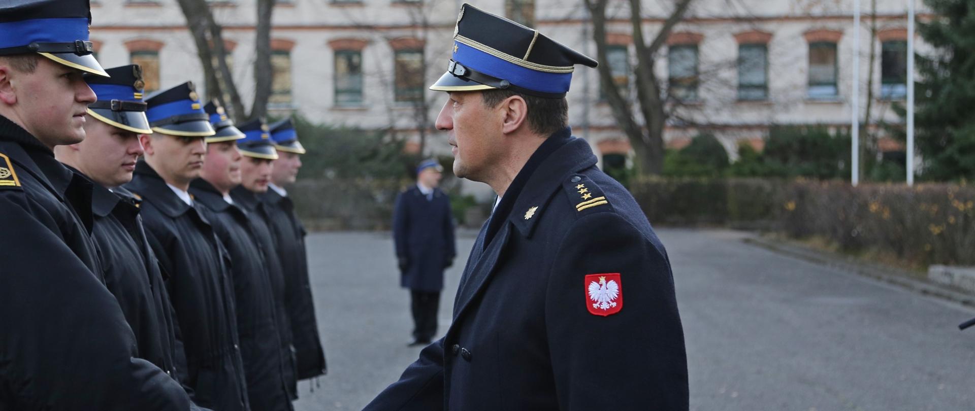 Komendant Szkoły gratuluje awansu podając rękę wyróżnionemu kadetowi. Obok stojący w szeregu kadeci