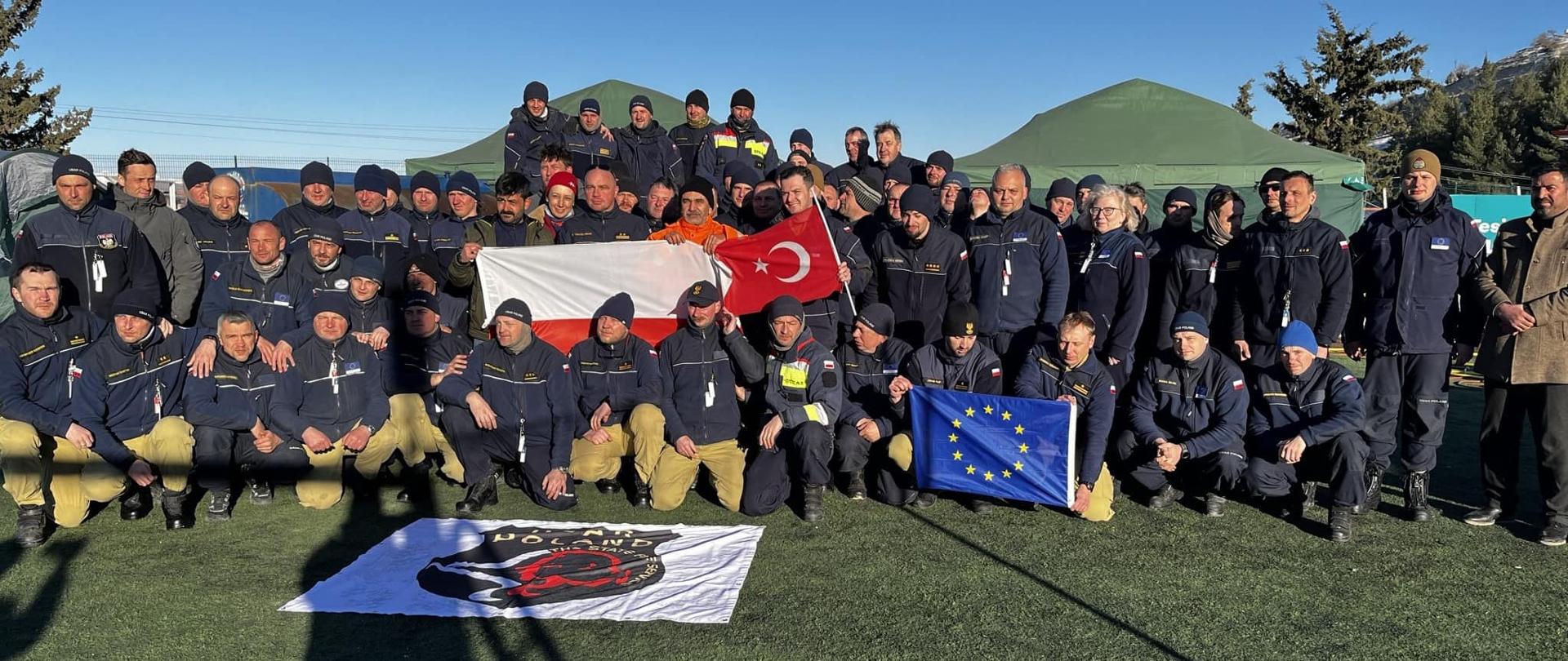Grupowe zdjęcie strażaków w Turcji, trzymają w dłoniach flagi Polski i Turcji