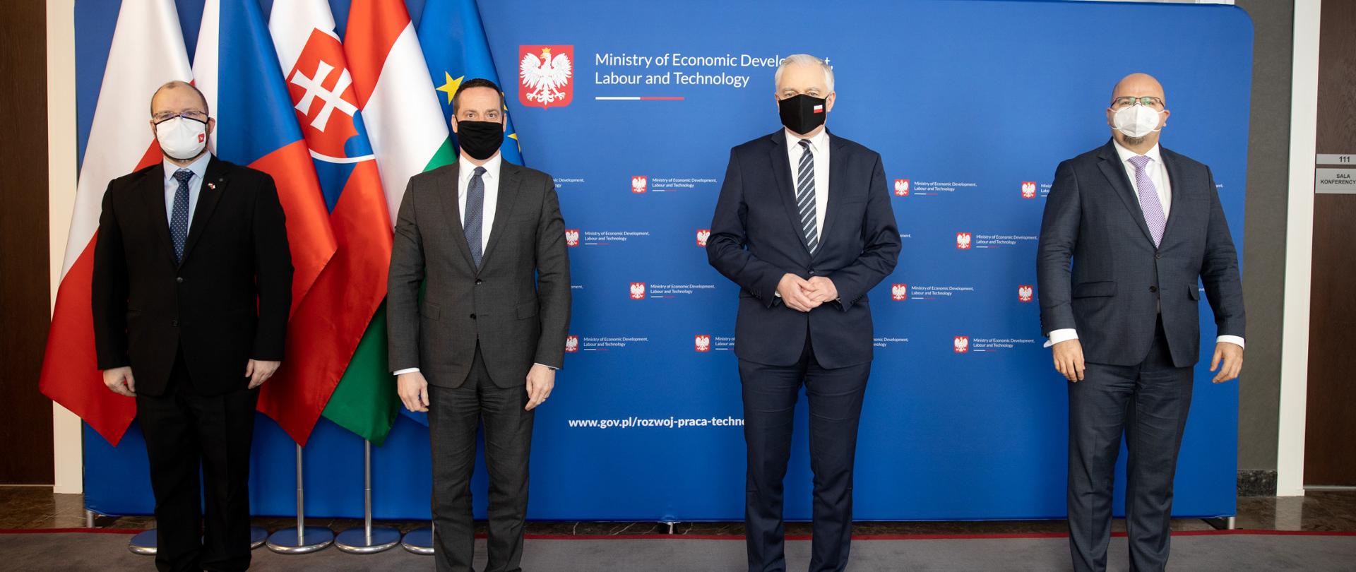 Premier Gowin z Ambasadorami Grupy Wyszehradzkiej na tle ścianki ministerstwa i flag czterech krajów.