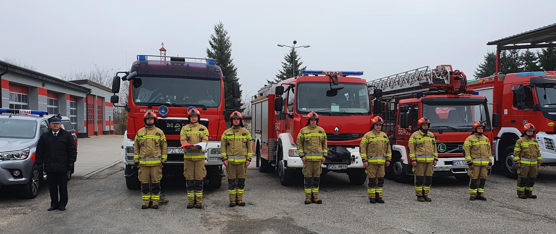 Na zdjęciu strażacy wraz z dowódcą w tle samochody strażackie.