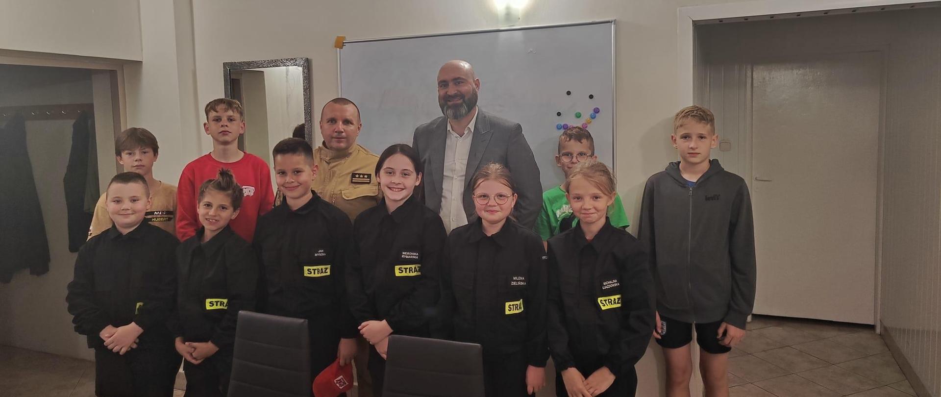 Świetlica remizy OSP Frombork. Na zdjęciu stoją dzieci w mundurkach oraz Burmistrz Fromborka oraz Komendant Powiatowy.