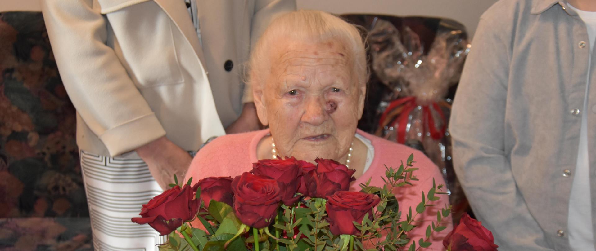 Na zdęciu Jubilatka. Trzyma bukiet czerwonych róż. 