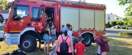 Dorośli i dzieci wsuadają do samochodu strażackiego.