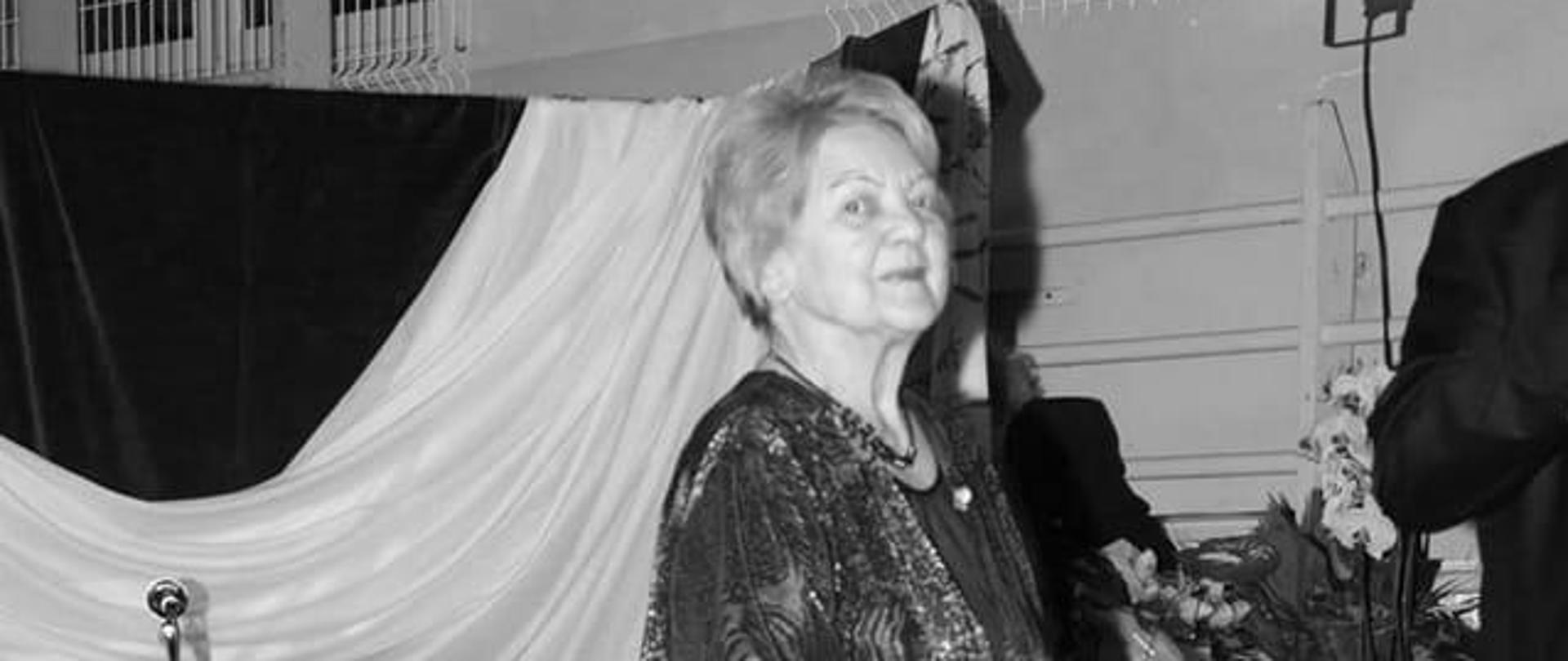 Czarno-białe zdjęcie na który Krystyna Lubos stoi na tle sceny