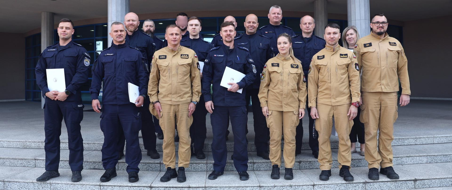 Pamiątkowe zdjęcie grupowe funkcjonariuszy Policji uczestniczących w szkoleniu z zakresu CBRNE (11 osób) w towarzystwie Zastępcy Komendanta Centralnej Szkoły PSP, kobiety oraz funkcjonariuszki i dwóch funkcjonariuszy CS PSP