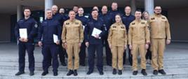 Pamiątkowe zdjęcie grupowe funkcjonariuszy Policji uczestniczących w szkoleniu z zakresu CBRNE (11 osób) w towarzystwie Zastępcy Komendanta Centralnej Szkoły PSP, kobiety oraz funkcjonariuszki i dwóch funkcjonariuszy CS PSP