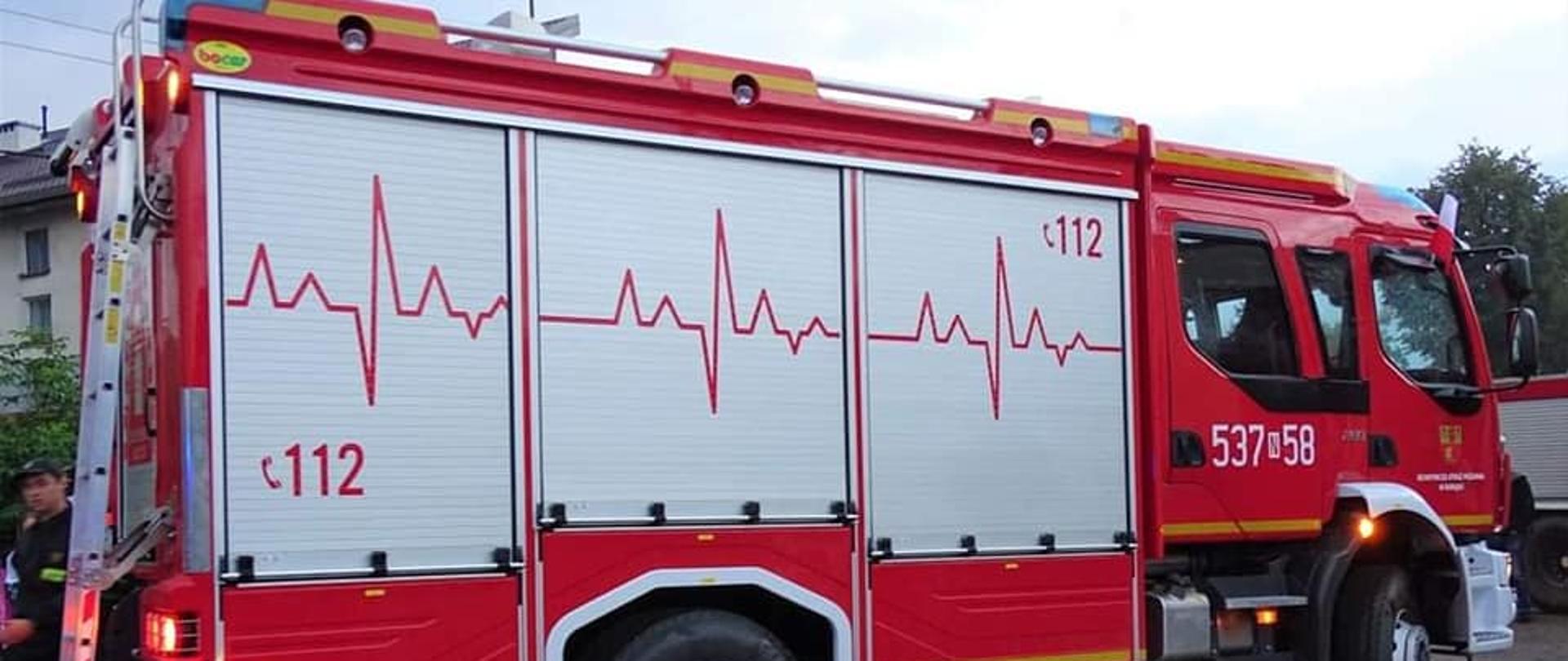 Nowy samochód pożarniczy stoi. Widoczny bok pojazdu. 