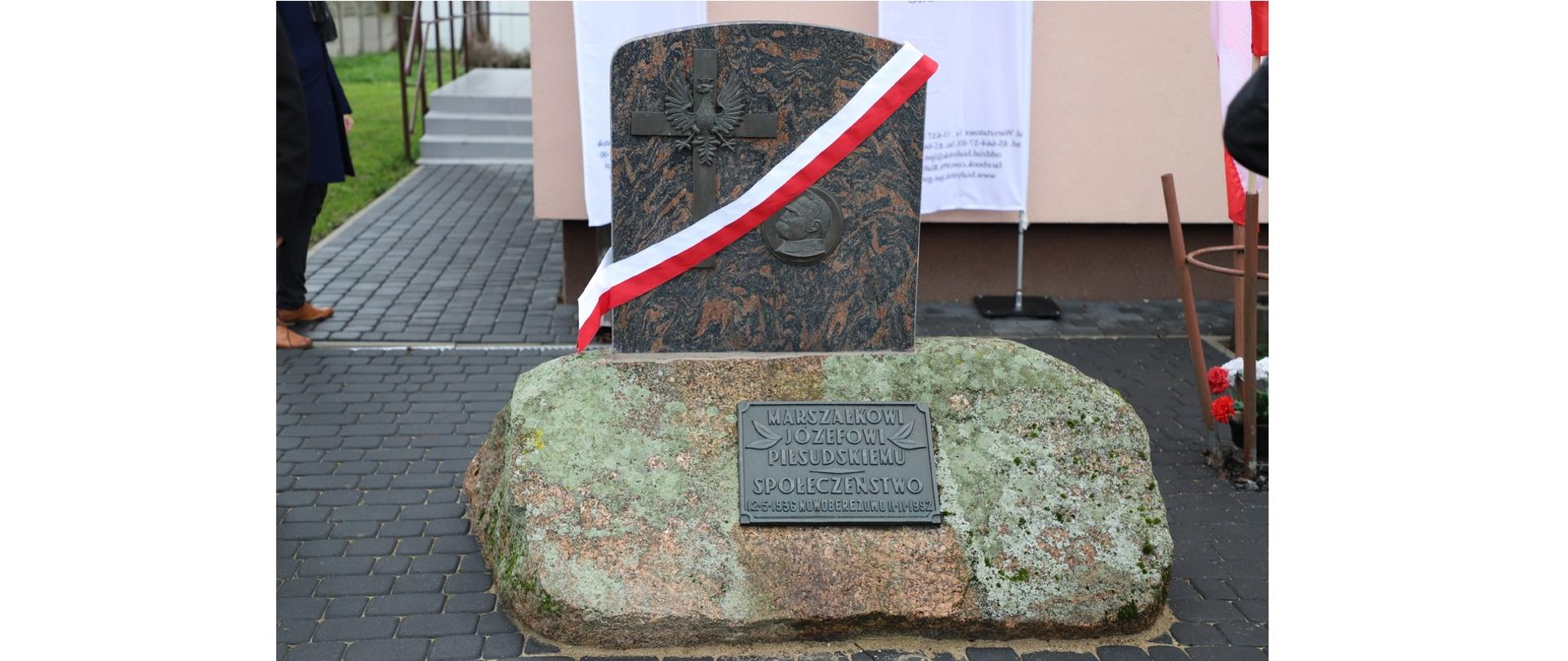 Przed budynkiem stoi pomnik. Na kamieniu znajduje się tablica z napisem " Marszałkowi Józefowi Piłsudskiemu Społeczeństwo. Nad kamieniem jest tablica granitowa z podobizna Józefa Piłsudskiego obok krzyż i orzeł.