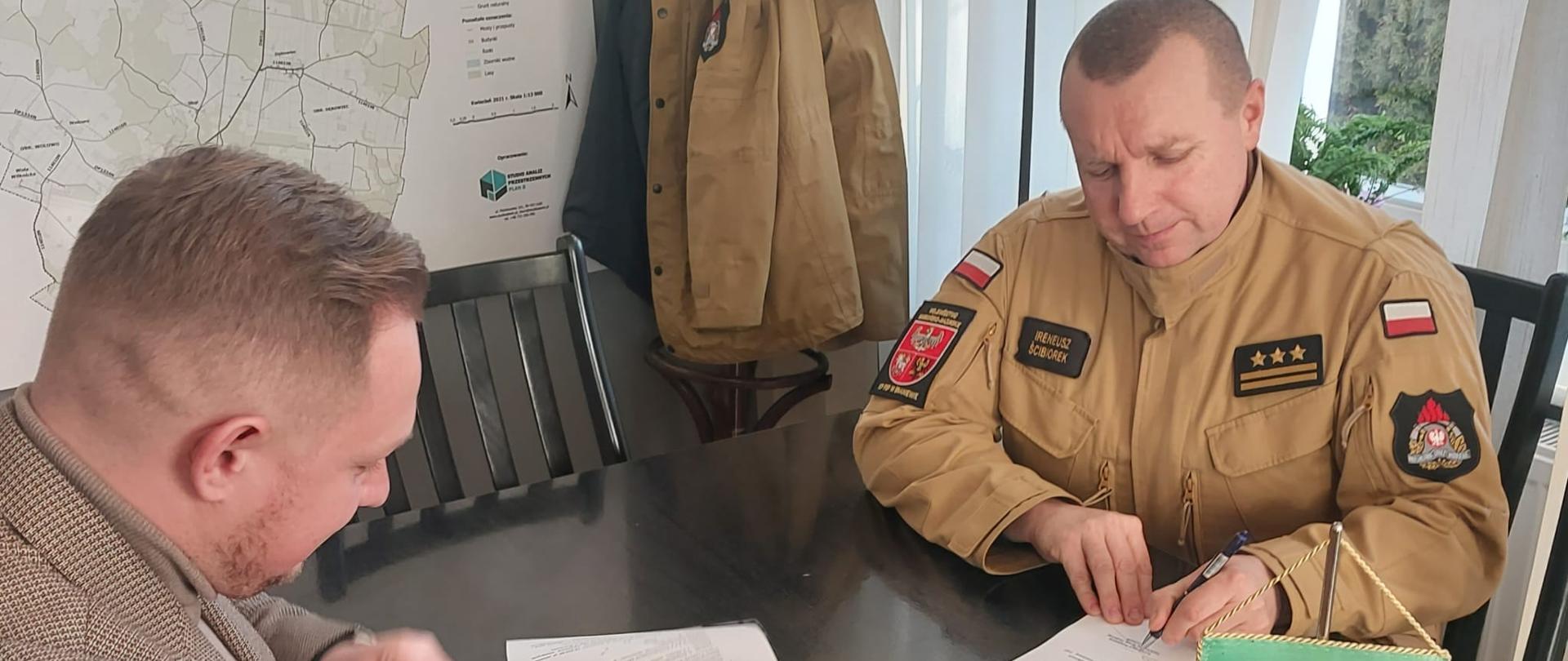 Na zdjęciu z prawej strony komendant powiatowy z lewej wójt gminy Lelkowo, podpisują dokumenty.