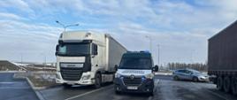 Kontrola drogowa: samochód inspekcji w centrum, po lewej ciężarówka z naczepą, po prawej w tle radiowóz podczas zatrzymania nietrzeźwego kierowcy