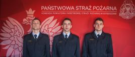Zdjęcie przedstawia uroczystą zbiórkę, podczas której odbyło się ślubowanie nowych funkcjonariuszy. Na zdjęciu widzimy trzech strażaków po uroczystym ślubowanie. Zdjęcie wykonane w porze dziennej na sali konferencyjnej.