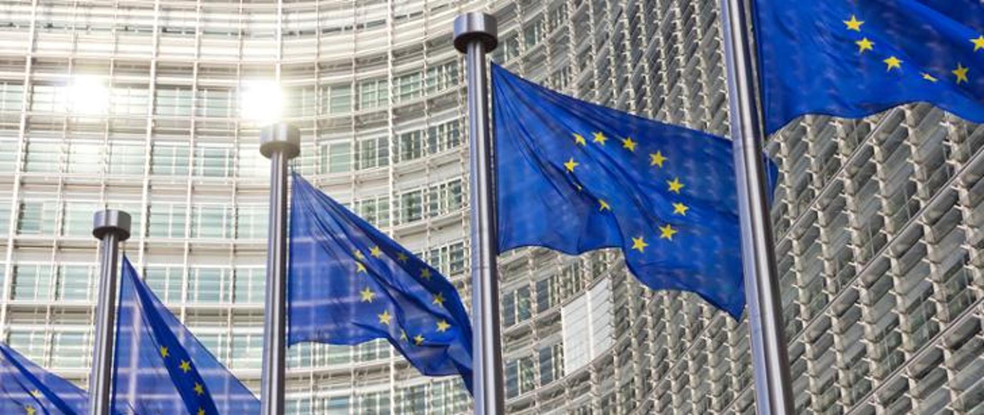 Flagi Unii Europejskiej na tle budynku Komisji Europejskiej