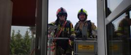 Na zdjęciu widoczni dwaj strażacy w koszu podnośnika hydraulicznego oczekujący na odbiór ewakuowanego na noszach poszkodowanego podczas ćwiczeń na oddziale geriatrycznym w szpitalu specjalistycznym w Gorlicach.