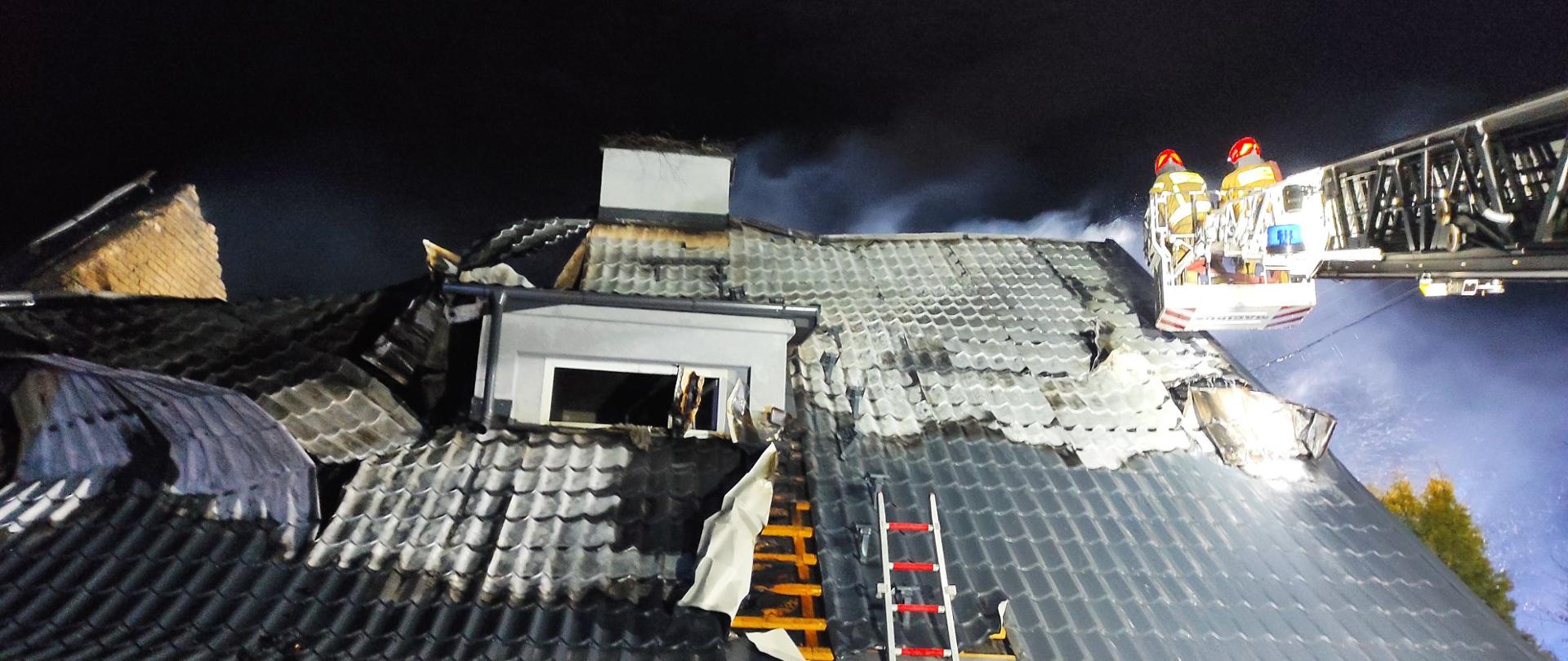 Spalony dach pokryty blachodachówką. Z prawej strony widać drabinę mechani9czna strażacką.