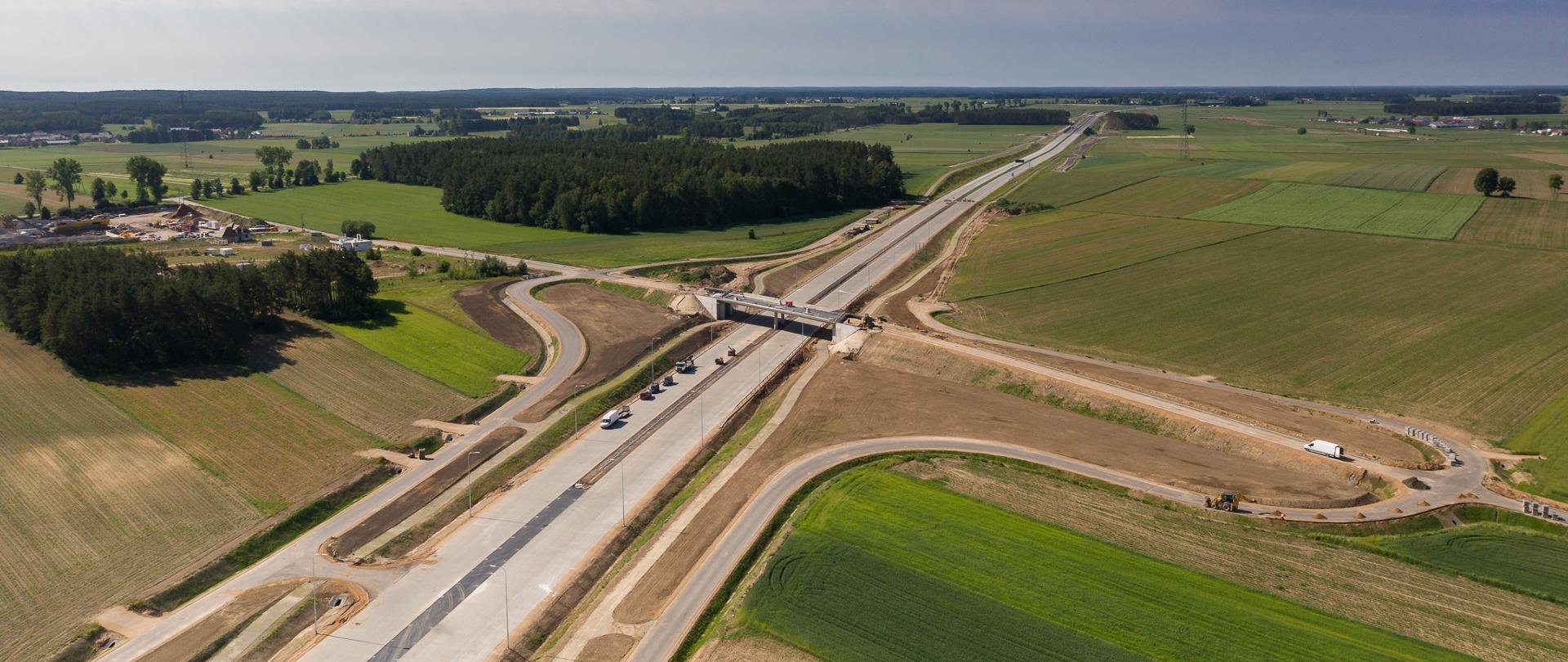 Budowa drogi ekspresowej S61 Łomża Południe - Łomża Zachód. W tle widać zabudowania, pola uprawne oraz las.