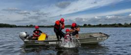 Strażacy wciągają do łódki poszkodowanego, pozoranta