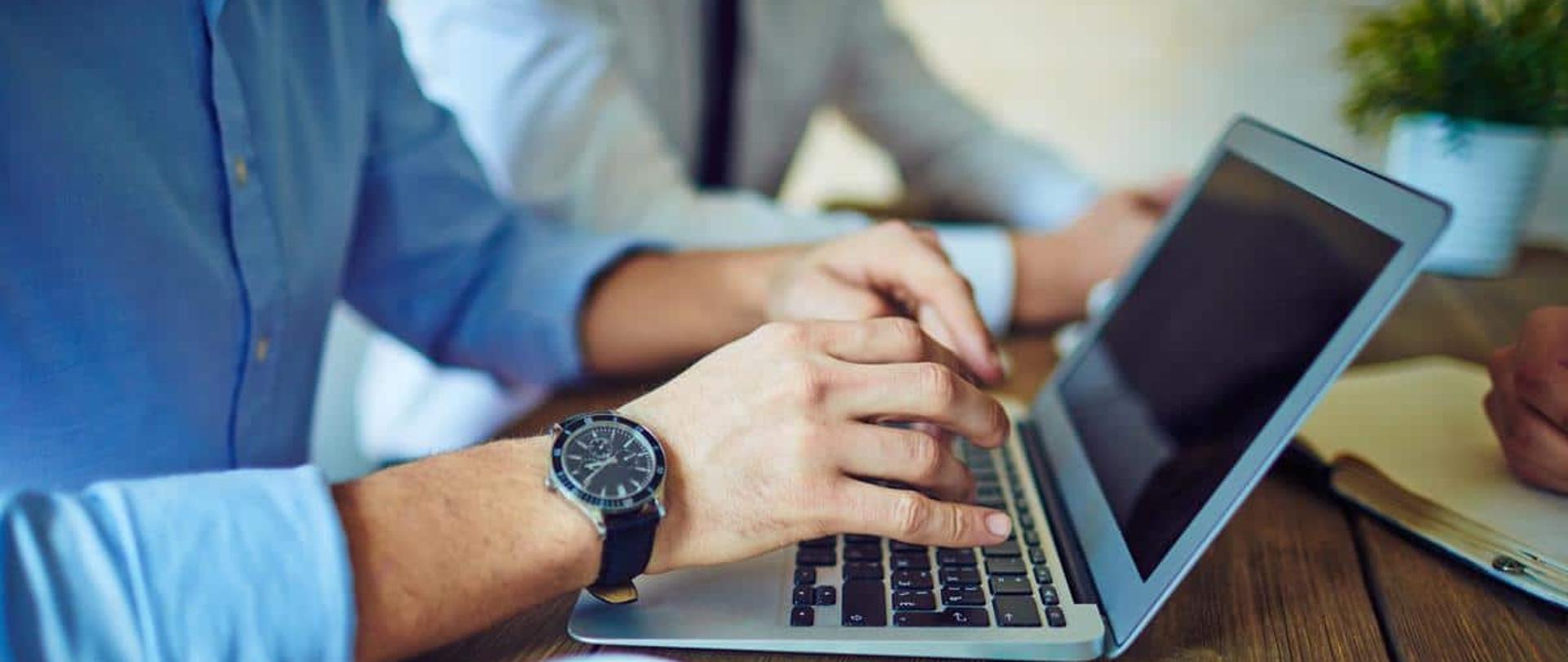 Mężczyzna przy kawie, piszący na laptopie.