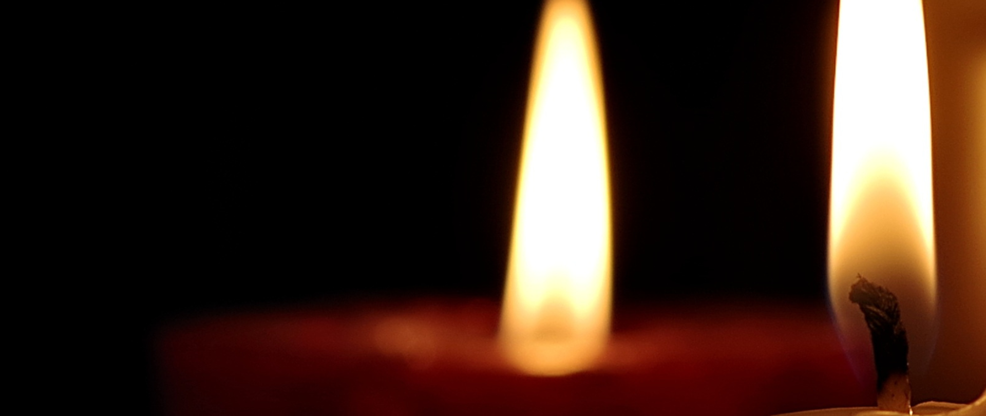 Plakat ze szczegółami koncertu na czarnym tle i zdjęciem płonących świec