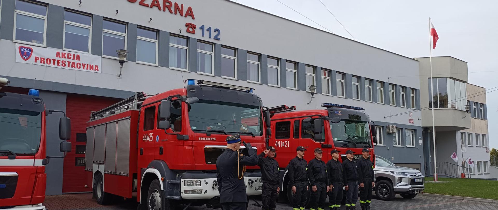 Zdjęcie przedstawia strażaków w umundurowaniu oddających honory i śpiewających hymn Rzeczypospolitej Polskiej
