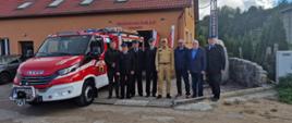 Strażacy Państwowej Straży Pożarnej ochotniczej straży pożarnej oraz przedstawiciele Urzędu Gminy Parchowo stoją w rzędzie obok samochodu gaśniczego.