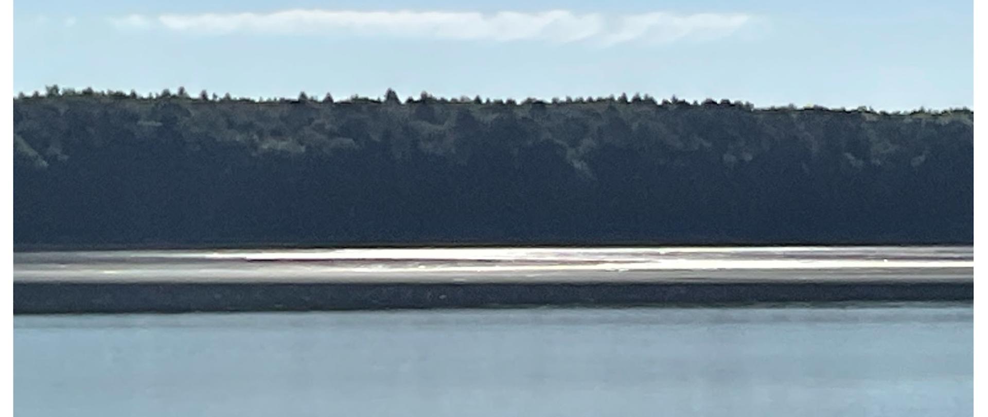 Krajobraz. Jest ciepły i słoneczny wrześniowy dzień. Tafla wody Zalewu Zemborzyckego. W tle widać na przeciwko brzeg i pas zieleni. 