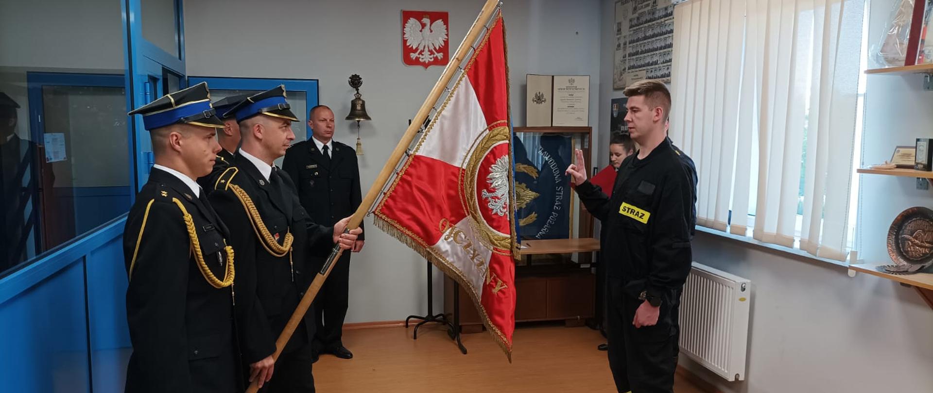 Na zdjęciu widoczny poczet sztandarowy i funkcjonariusze. Nowo przyjęty strażak składa ślubowanie.
