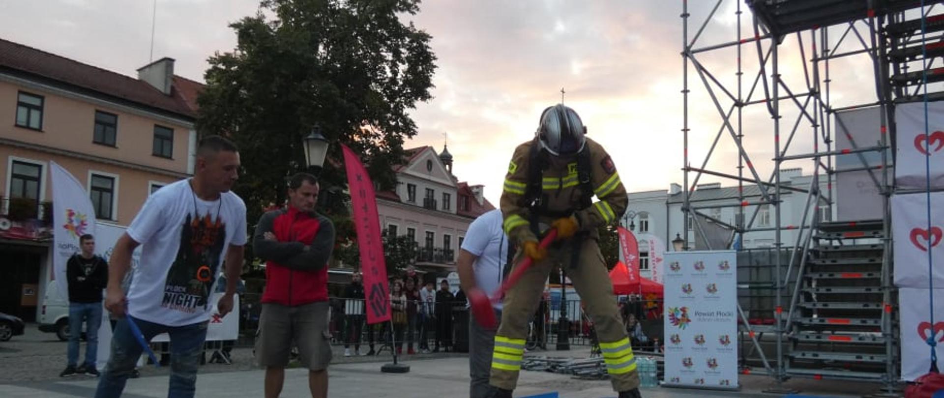 Strażak uderza młotem w stalową belkę